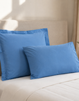 Fronhas Oxford Royal azul em percal de algodão sobre cama – vista lifestyle com almofada quadrada e retangular - BellaGoma
