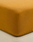 Pormenor de duas Fronhas Charming ocre sobre roupa de cama branca, revelando a textura suave da flanela chambray - BellaGoma
