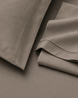 Pormenor do tecido e das bainhas da roupa de cama Stone em tons neutros.