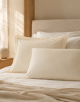Fronhas Oxford Royal cru em percal de algodão dispostas em cama com luz natural – ambiente quarto sereno - BellaGoma