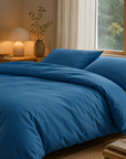 Capa de edredão Charming em flanela chambray cor Azul sobre cama em quarto aconchegante com iluminação quente e janela com chuva — BellaGoma