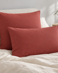 Fronhas Charming em Tijolo numa cama com roupa em tons claros