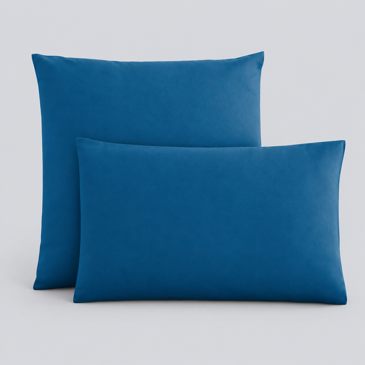 Fronhas Charming em Azul/Petróleo sobrepostas sobre fundo cinzento