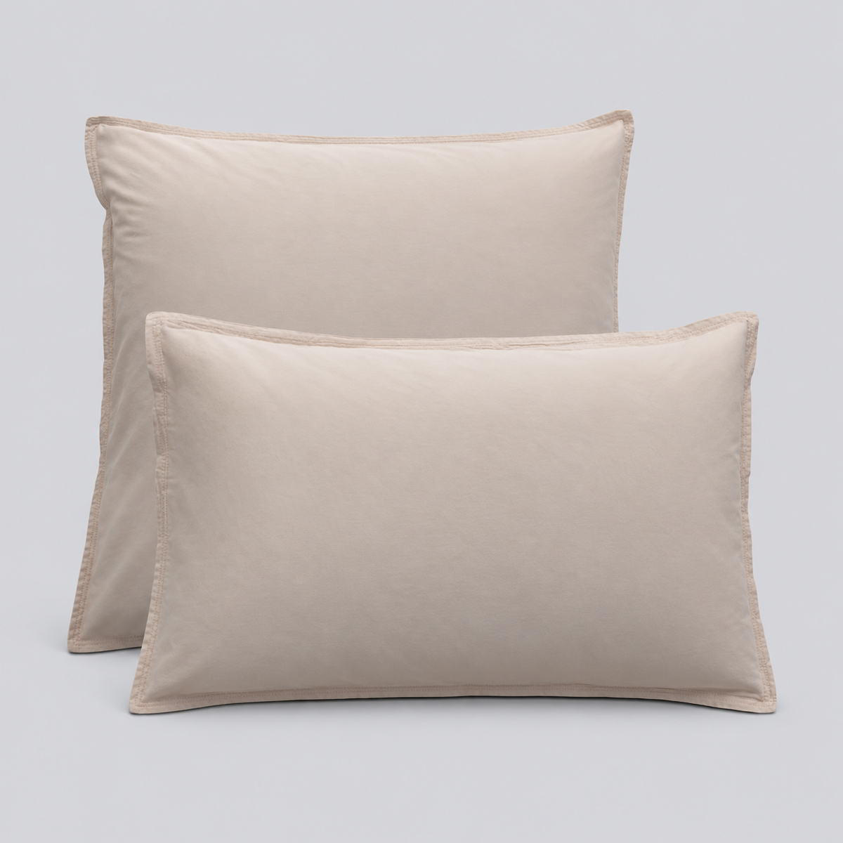 Duas almofadas com fronhas Stone bege em percale 100% algodão sobre fundo cinzento-claro.