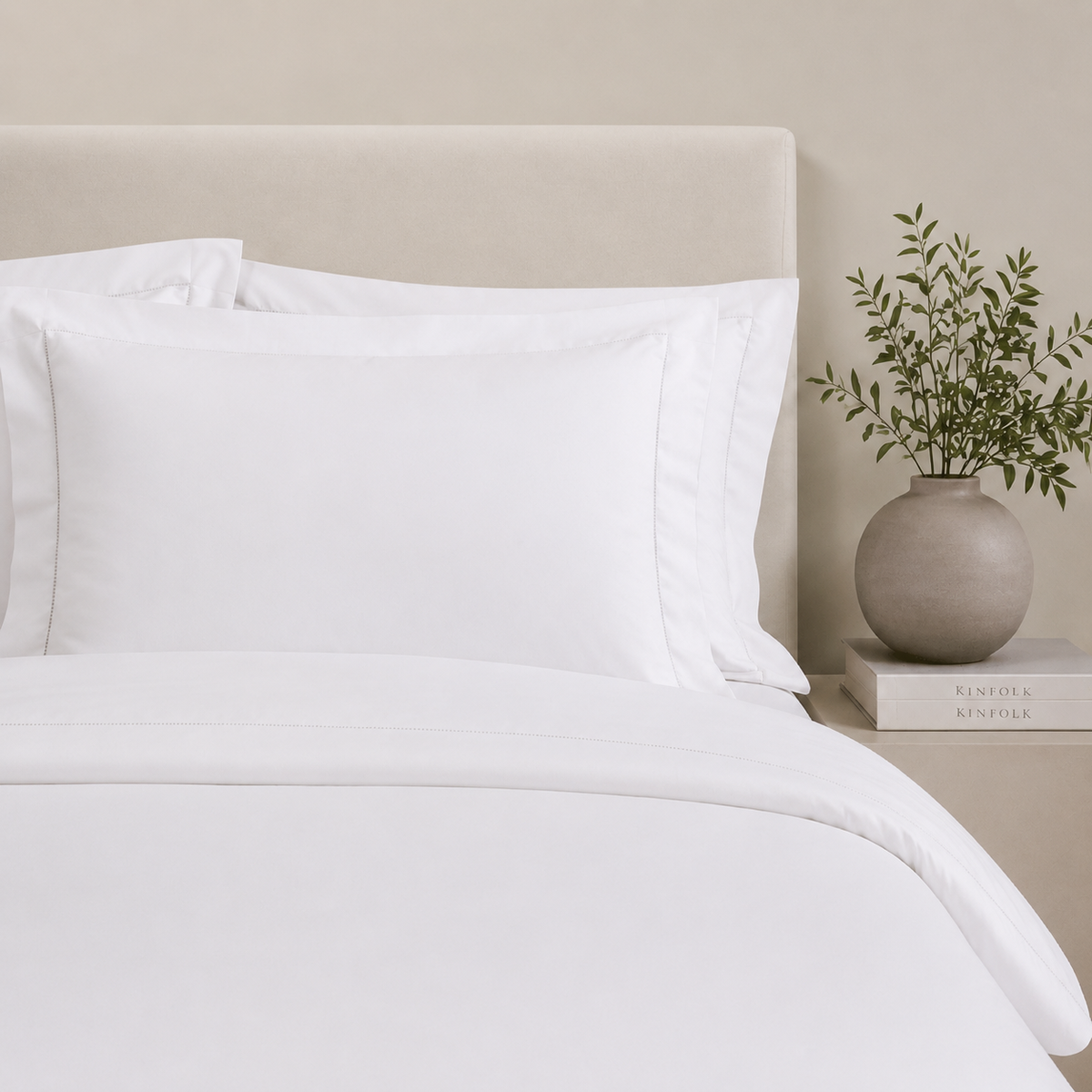 Fronhas BellaLux brancas sobre cama elegante em tons neutros