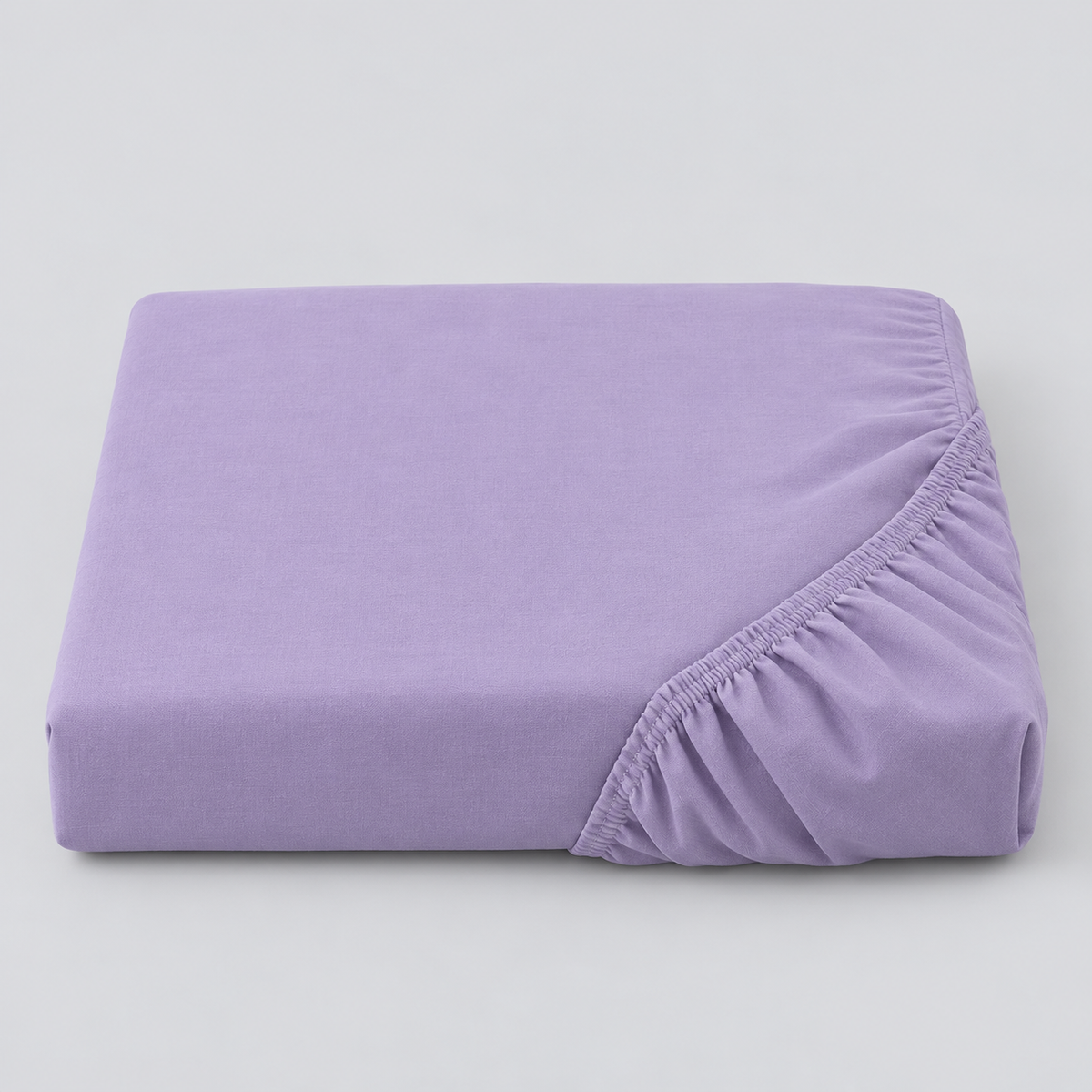 Lençol ajustável Stone lavanda dobrado, com o elástico visível sobre fundo cinzento.