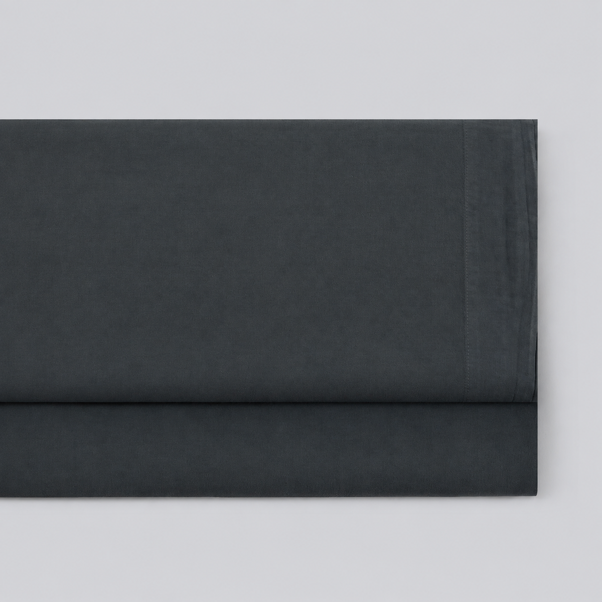 Lençol de cima Stone cinza grafite em percale 100% algodão, dobrado com a bainha superior visível.