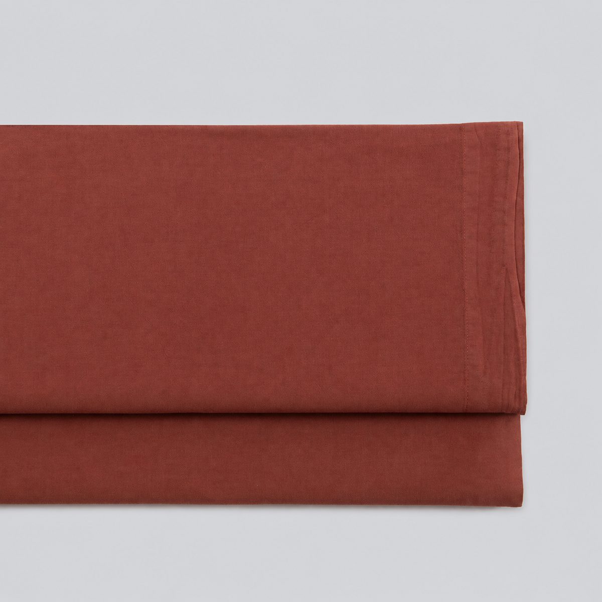 Lençol de cima Stone cor de tijolo em percale 100% algodão, dobrado com a bainha superior visível.