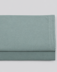 Lençol de cima Stone verde em percale 100% algodão, dobrado com a bainha superior visível.